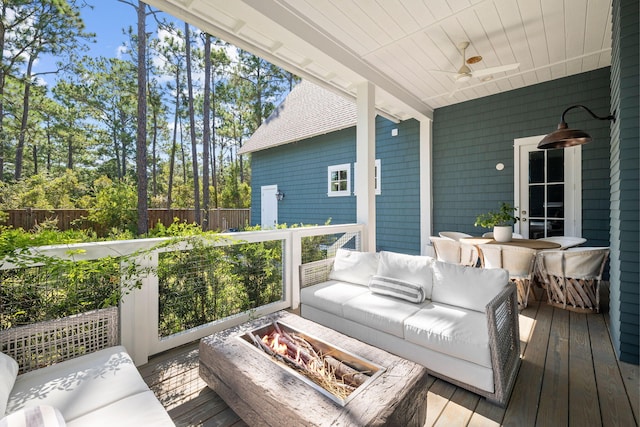 deck featuring ceiling fan and an outdoor living space with a fire pit