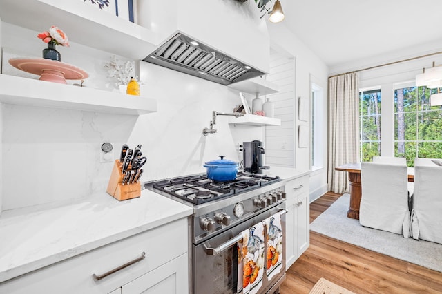 kitchen featuring light hardwood / wood-style flooring, premium range hood, white cabinets, light stone counters, and stainless steel range