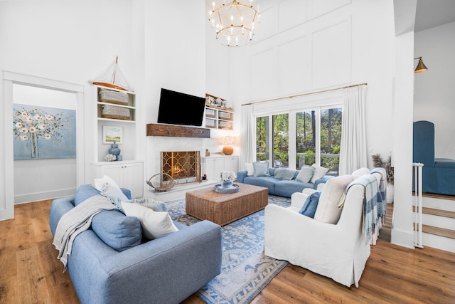 living room with a towering ceiling, a notable chandelier, and wood-type flooring