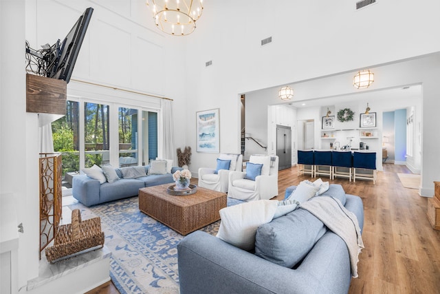 living room with a high ceiling, light hardwood / wood-style flooring, and an inviting chandelier