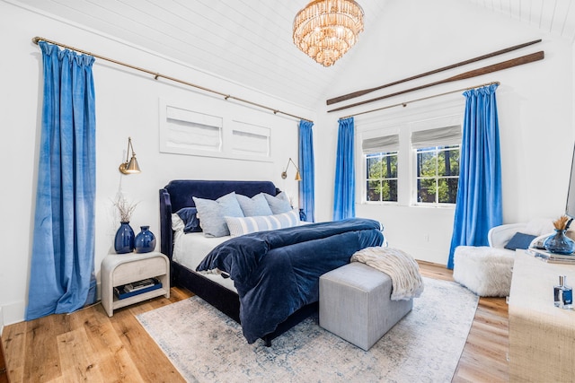 bedroom featuring vaulted ceiling, light hardwood / wood-style flooring, and a chandelier