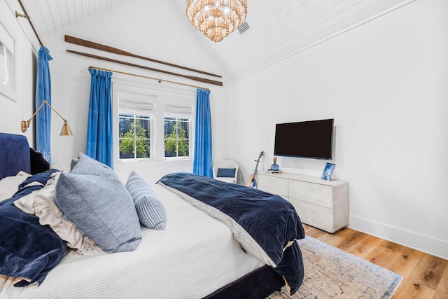 bedroom featuring a notable chandelier, vaulted ceiling, and hardwood / wood-style floors