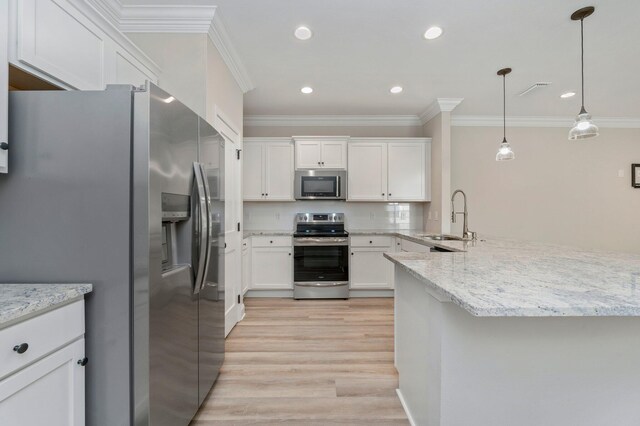 kitchen featuring appliances with stainless steel finishes, sink, decorative light fixtures, white cabinets, and light hardwood / wood-style flooring