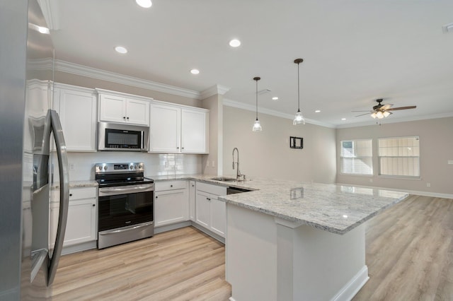 kitchen featuring appliances with stainless steel finishes, sink, hanging light fixtures, white cabinets, and light hardwood / wood-style flooring