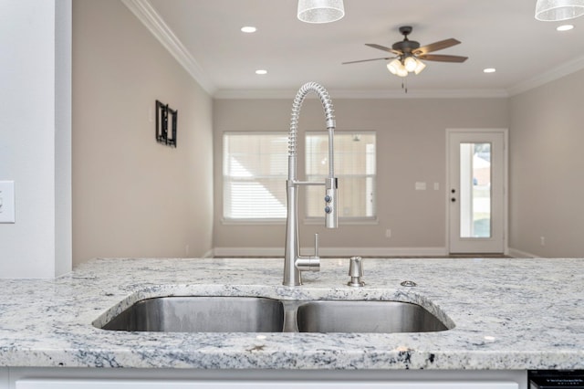 kitchen with light stone counters, ornamental molding, sink, and ceiling fan