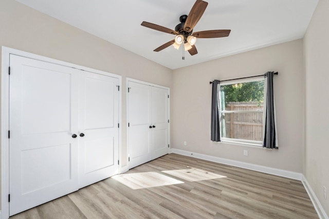 unfurnished bedroom with multiple closets, light hardwood / wood-style floors, and ceiling fan