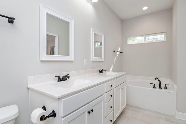 bathroom with toilet, vanity, and a bathtub