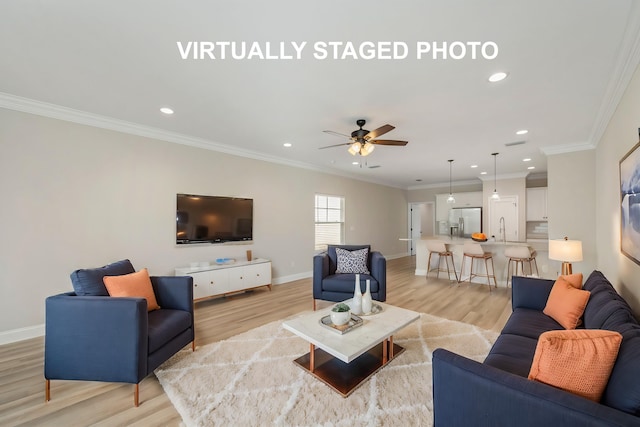 living room with ornamental molding, sink, light wood-type flooring, and ceiling fan