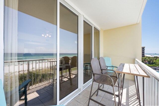 balcony with a water view and a view of the beach