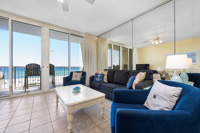 living room featuring a water view, ceiling fan, and light tile patterned floors