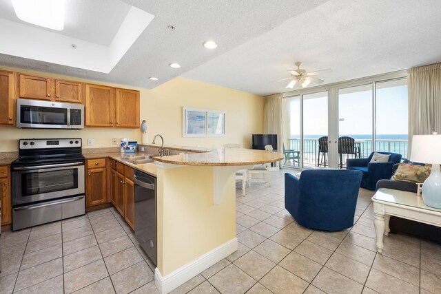 kitchen with appliances with stainless steel finishes, sink, kitchen peninsula, ceiling fan, and a breakfast bar