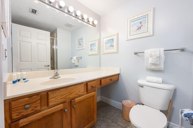 bathroom featuring tile patterned flooring, vanity, toilet, and an enclosed shower