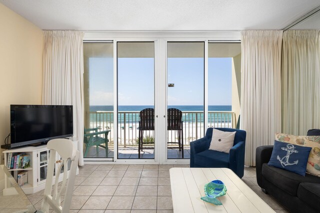 tiled living room with a textured ceiling, a beach view, and a water view