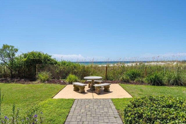 view of home's community with a water view, a yard, and a patio