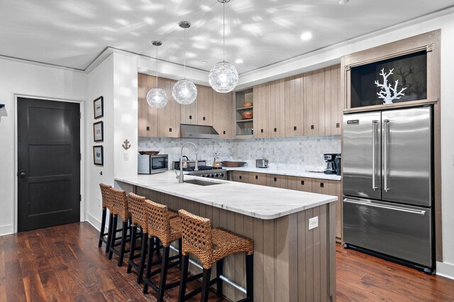 kitchen with decorative light fixtures, appliances with stainless steel finishes, dark hardwood / wood-style floors, kitchen peninsula, and decorative backsplash