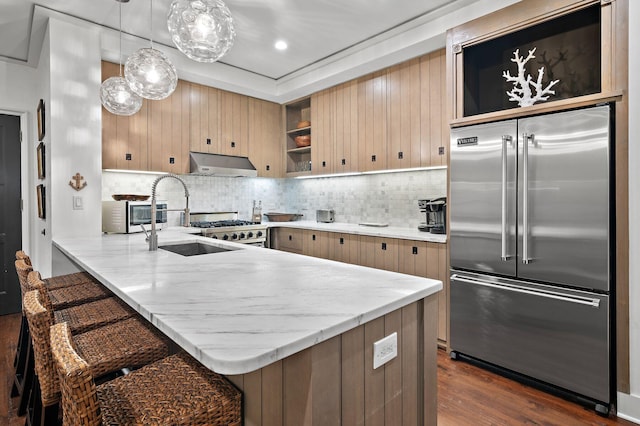 kitchen with stainless steel appliances, kitchen peninsula, extractor fan, dark wood-type flooring, and decorative backsplash