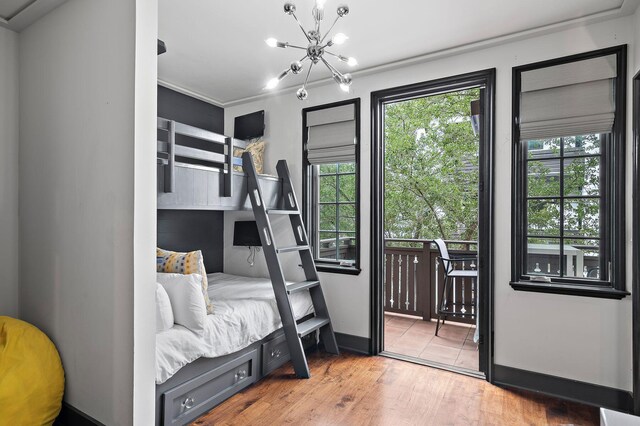 bedroom with ornamental molding, a chandelier, hardwood / wood-style floors, and access to exterior