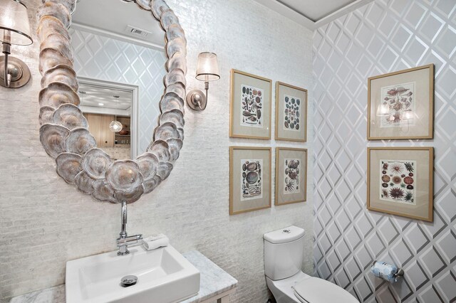 bathroom featuring tile walls, toilet, sink, and ornamental molding