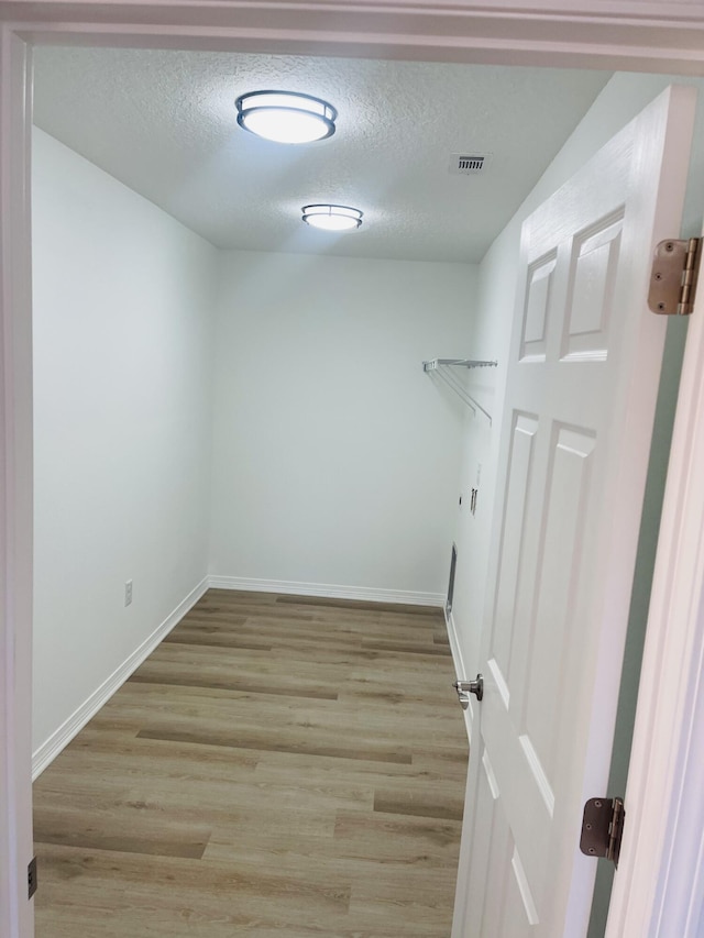 laundry area with a textured ceiling and light wood-type flooring