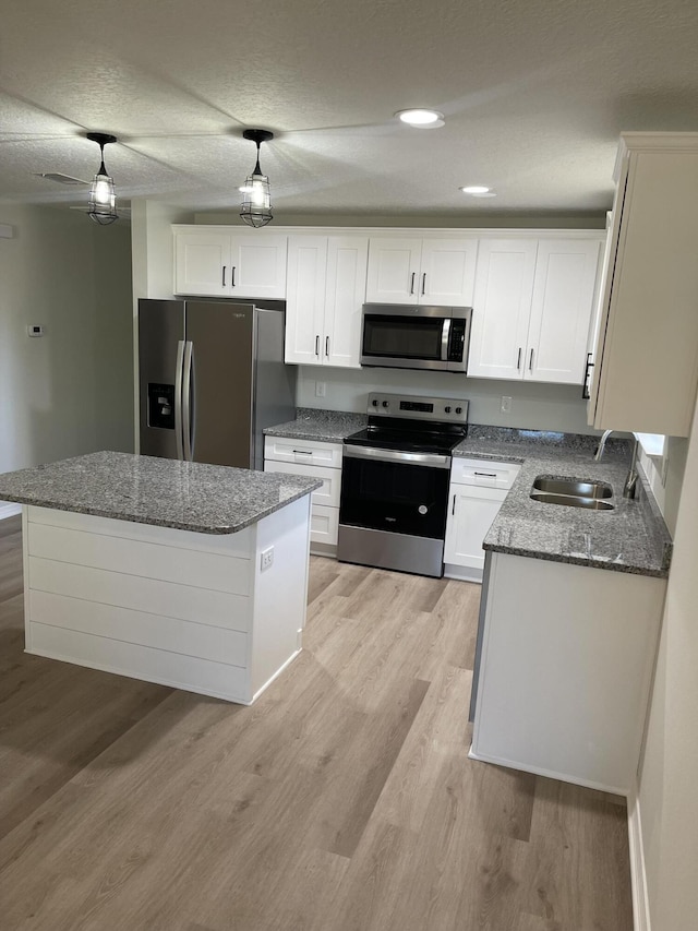 kitchen featuring sink, light hardwood / wood-style flooring, light stone countertops, white cabinetry, and stainless steel appliances