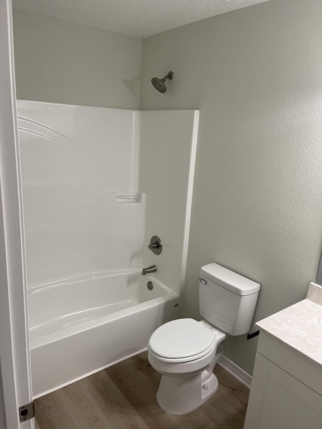 full bathroom with a textured ceiling, toilet,  shower combination, vanity, and hardwood / wood-style flooring