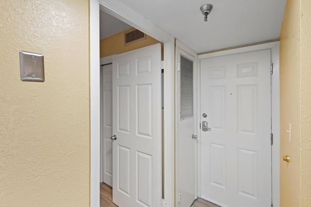 hallway with a textured wall and wood finished floors