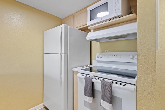 kitchen featuring white appliances, under cabinet range hood, light countertops, baseboards, and a textured wall