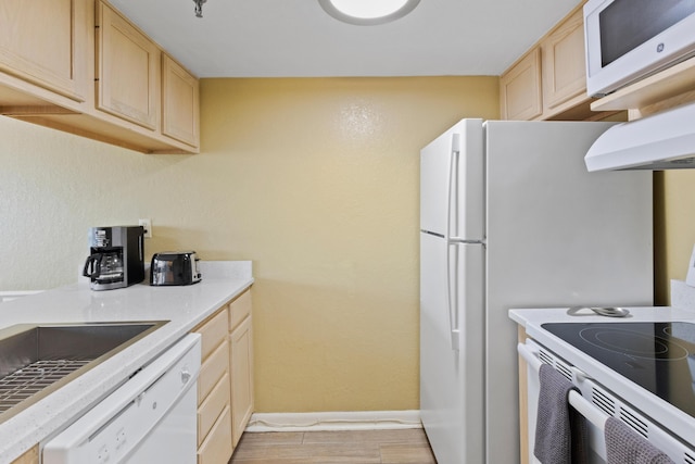 kitchen featuring light brown cabinetry, white appliances, under cabinet range hood, baseboards, and light wood-style floors