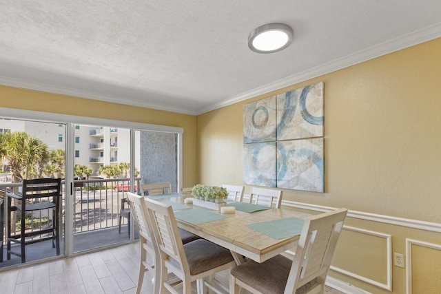 dining area with crown molding, light hardwood / wood-style flooring, and a textured ceiling