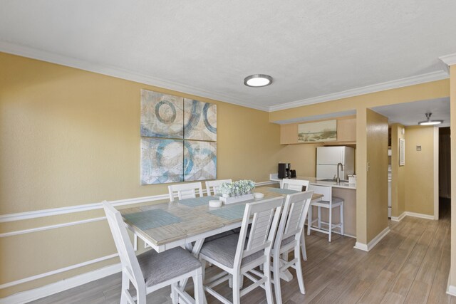 dining area with ornamental molding and light hardwood / wood-style floors