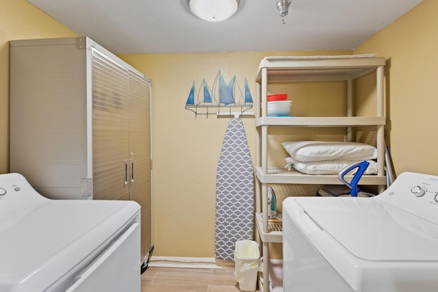 laundry area with separate washer and dryer, light wood-style flooring, and baseboards