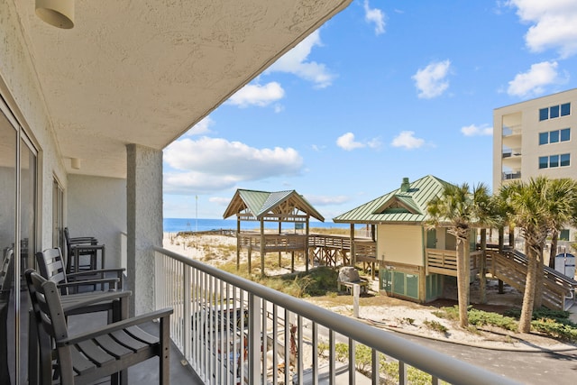 balcony with a water view and a view of the beach