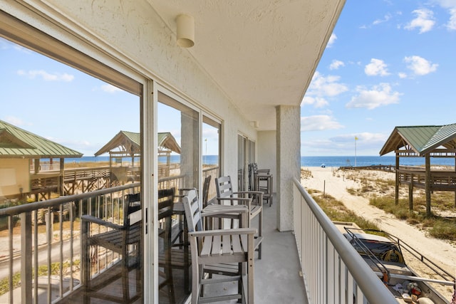 balcony with a water view and a view of the beach