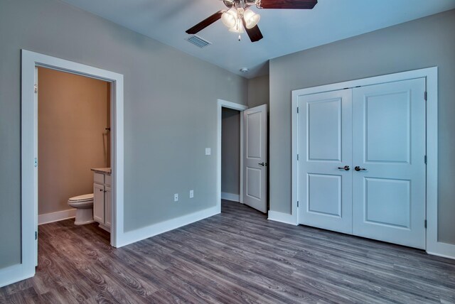 unfurnished bedroom featuring ceiling fan, a closet, ensuite bath, and dark hardwood / wood-style floors