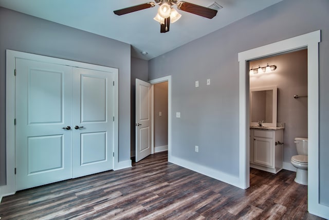 unfurnished bedroom featuring ceiling fan, dark hardwood / wood-style floors, a closet, ensuite bath, and sink