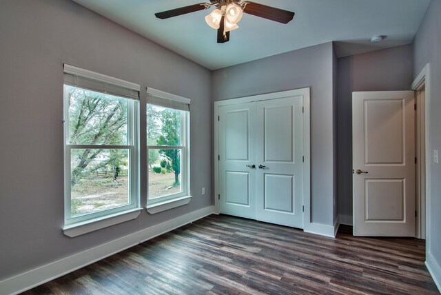 unfurnished bedroom with ceiling fan, dark hardwood / wood-style floors, and a closet