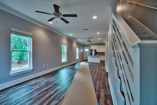 unfurnished living room with ceiling fan, ornamental molding, and dark hardwood / wood-style floors