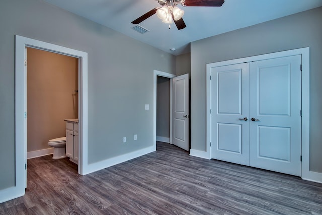 unfurnished bedroom featuring dark hardwood / wood-style flooring, a closet, connected bathroom, and ceiling fan