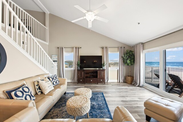 living room with a wealth of natural light, ceiling fan, light hardwood / wood-style floors, and high vaulted ceiling