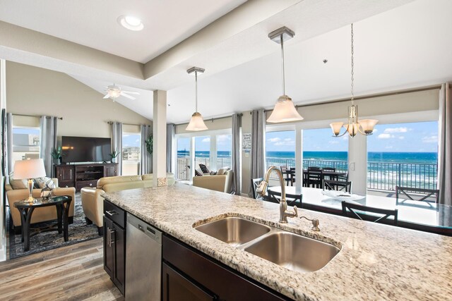 kitchen featuring light wood-type flooring, hanging light fixtures, ceiling fan with notable chandelier, sink, and a water view