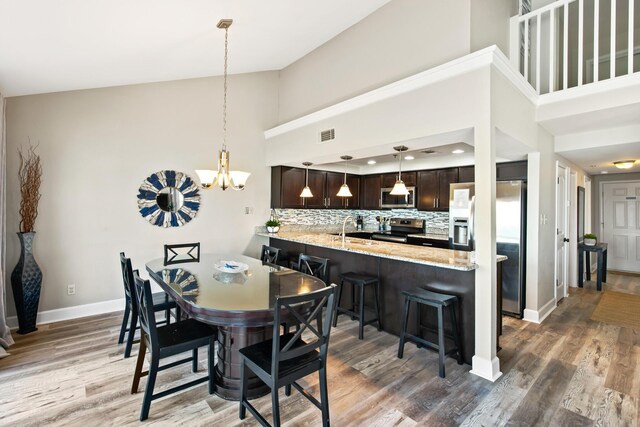 dining space featuring sink, a notable chandelier, high vaulted ceiling, and dark hardwood / wood-style floors