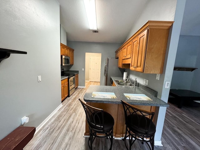 kitchen with hardwood / wood-style floors, a breakfast bar area, stainless steel appliances, and sink