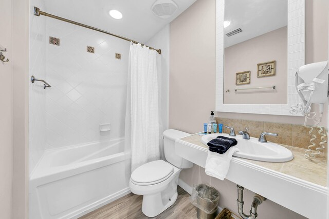 full bathroom with sink, toilet, shower / bath combo with shower curtain, and wood-type flooring