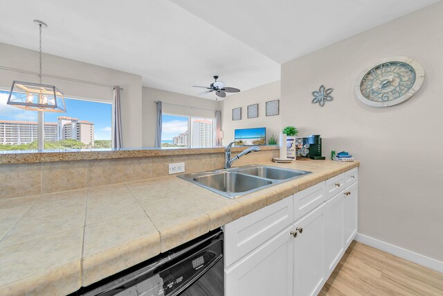 kitchen with sink, white cabinetry, light hardwood / wood-style floors, ceiling fan, and hanging light fixtures