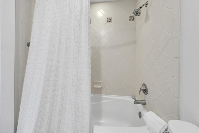 bathroom with shower / bathtub combination with curtain and toilet