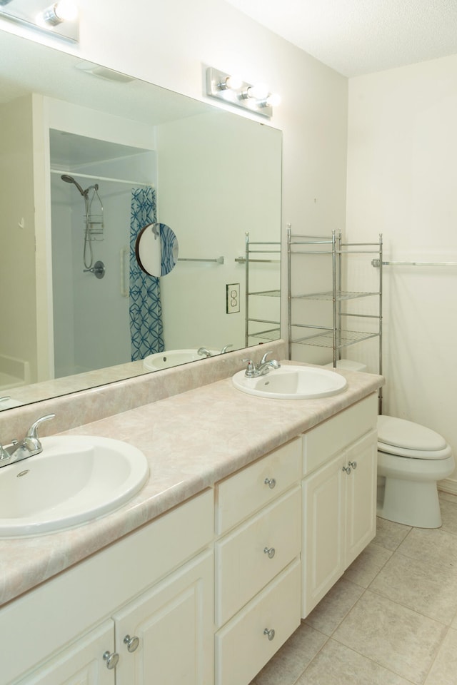 bathroom featuring tile patterned flooring, vanity, toilet, and walk in shower