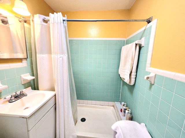 bathroom with tile walls, vanity, decorative backsplash, and walk in shower