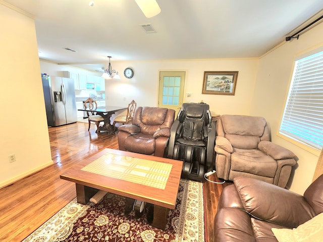 living room with wood-type flooring, ornamental molding, and ceiling fan