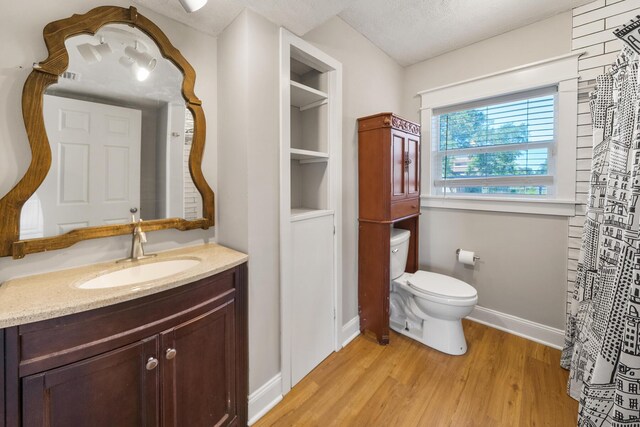 bathroom with a textured ceiling, toilet, vanity, and wood-type flooring