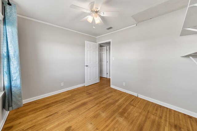 empty room featuring ceiling fan, light wood-type flooring, and crown molding